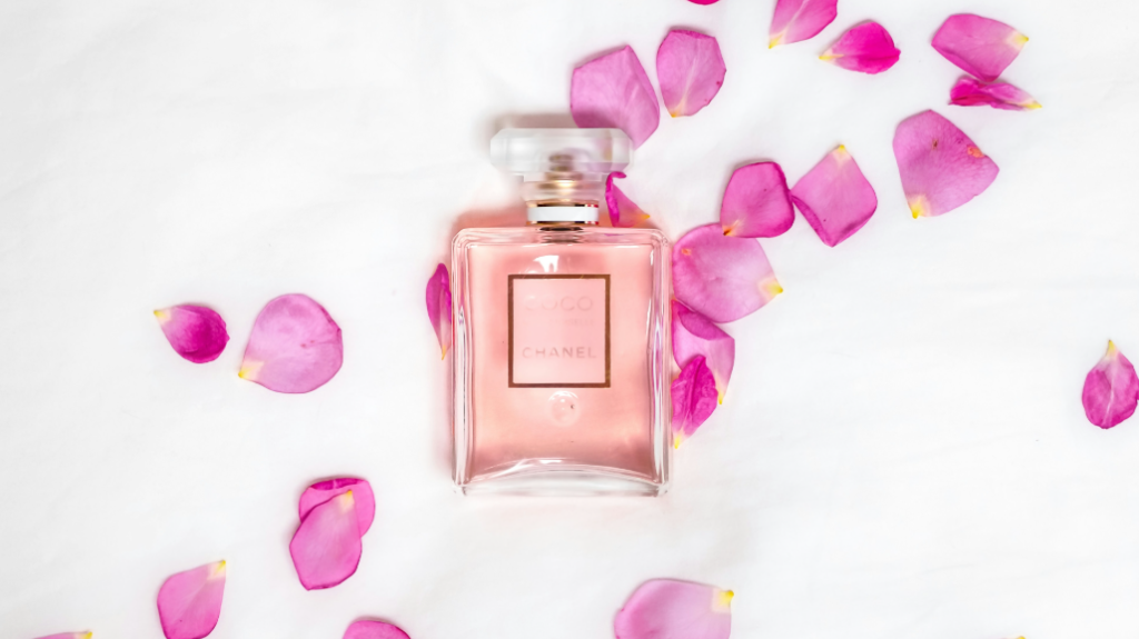 frasco de perfume coco mademoiselle chanel com pétalas de rosas ao fundo no site perfume e poesia