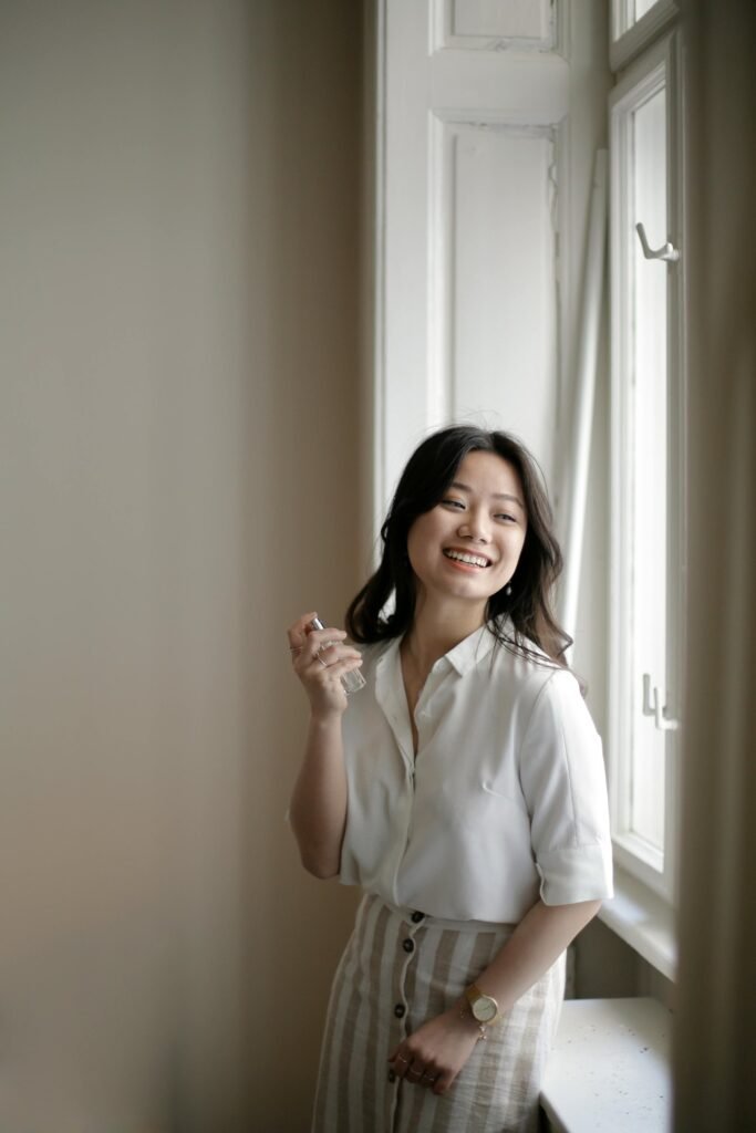 mulher segurando perfume e sorrindo em destaque no site perfume e poesia