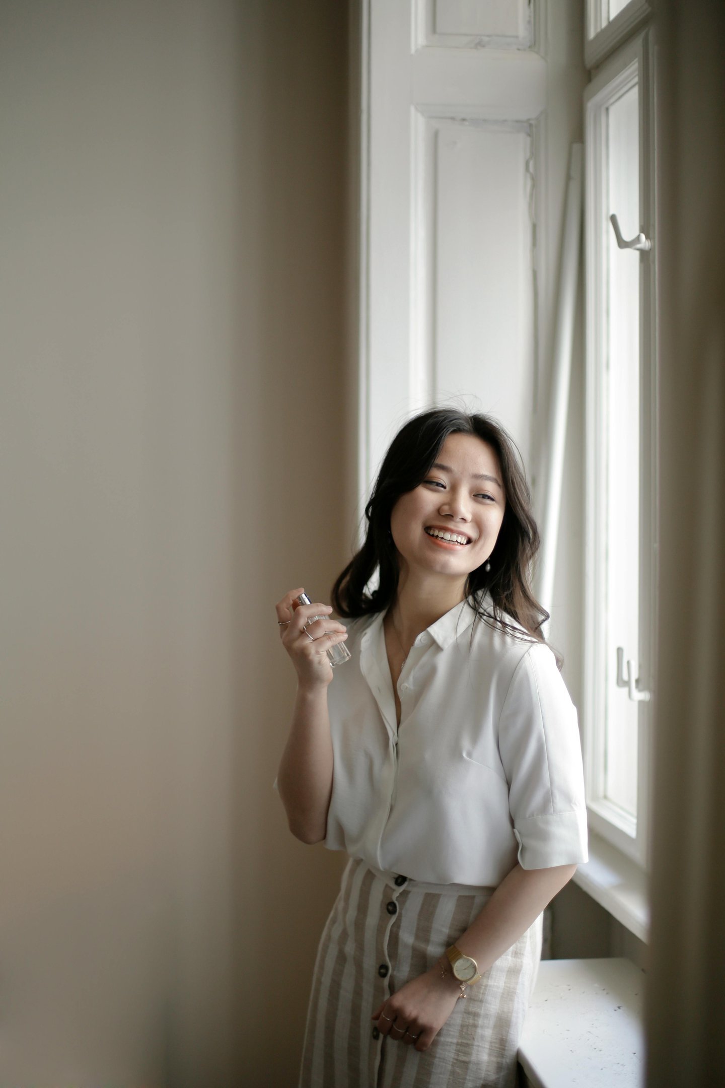 mulher segurando perfume e sorrindo em destaque no site perfume e poesia